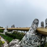 Explore the iconic Golden Bridge in Da Nang, Vietnam, held by giant stone hands amidst lush greenery.