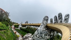 Explore the iconic Golden Bridge in Da Nang, Vietnam, held by giant stone hands amidst lush greenery.